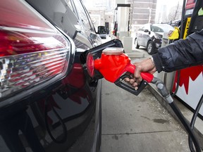 A person pumps gas into a black car in a Petro Canada gas station