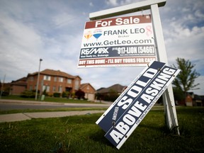 A real estate sign that reads "For Sale" and "Sold Above Asking" stands in front of housing in Vaughan, a suburb in Toronto.