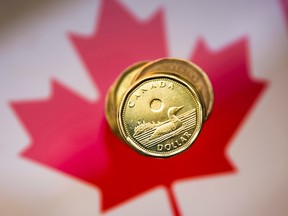 A Canadian dollar coin against a Canadian flag.