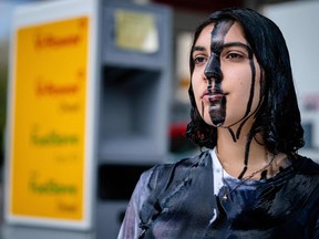 A protestor covered in black paint takes part in an action called by global environmental movement Extinction Rebellion and Dutch climate activist group Code Rood, at a Shell gas station in The Hague, on May 18, 2021 to protest against the policy of the Shell group, which according to the activists, chooses profit over the climate, nature and human lives.