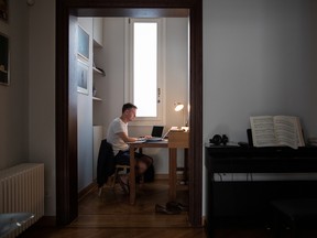 A remote worker at his kitchen table working on a laptop