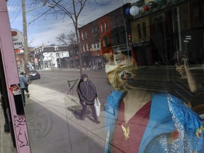 A mannequin displaying a protective mask in the window of a closed store on Queen St. West in Toronto.