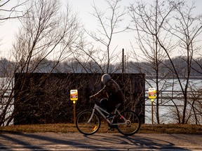 A man cycles past signposts marking the presence of Enbridge's Line 5 pipeline, which Michigan Governor Gretchen Whitmer ordered shut down in May 2021, in Sarnia, Ont.