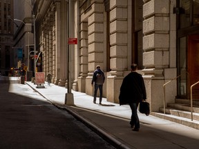 Pedestrians walk along a street in the financial district of New York