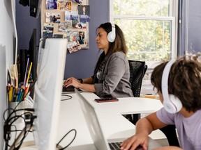 A woman working from home, sharing a desk with her son.