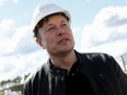 Elon Musk wearing a white construction helmet