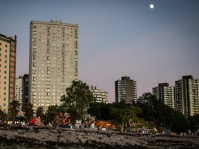 People sit on the sand at English Bay Beach amidst a heat wave, in Vancouver, B.C., on Monday, June 21, 2021.