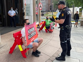 A police officer talks to a Greenpeace activist who demonstrates in front of the Norwegian oil and energy ministry in central Oslo, Norway June 24, 2021, a day after the country granted exploration oil licenses in the Arctic.