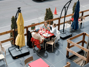 People eat on a restaurant patio in Montreal on May 28, 2021. Restaurants, non-essential retail stores, and providers of personal-care services “are going to be the key industries to watch in the months ahead,” one economist says.