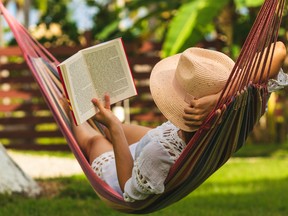 A woman relaxing on a hammock with a book.