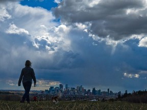 Storm clouds move in over walkers in Edworthy Park and the downtown Calgary skyline.