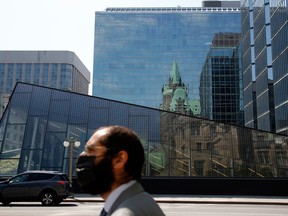 A pedestrian walks past the Bank of Canada building in Ottawa. If supply rigidities continue beyond 2022, continued fiscal and monetary stimulus may well fan inflation.