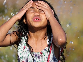 A child plays in water at a park during a heatwave.