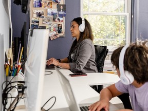 A woman in California works at her desk with her 10-year-old son nearby. More women in the workforce boosts growth and productivity.