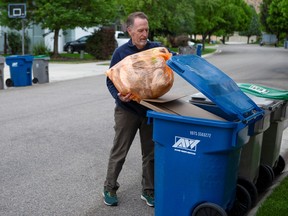 Boise resident David Garman places his orange Hefty EnergyBag into his recycling bin in Boise, Idaho, U.S., May 21, 2021. Picture taken May 21, 2021.