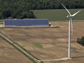 A wind turbine stands near a farm building with solar panels on the roof in Norfolk County near Simcoe, Ontario.