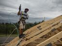 A worker nails plywood on the roof of a home under construction in Edmonton.