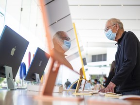 A customer wearing a protective mask tries out the Apple Inc. iMac computers at an Apple store in Palo Alto, California.