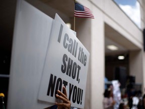 Anti-vaccine rally protesters hold signs outside of Houston Methodist Hospital in Houston, Texas.