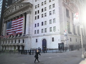 People pass the New York Stock Exchange (NYSE) on March 16, 2020 at Wall Street in New York City.