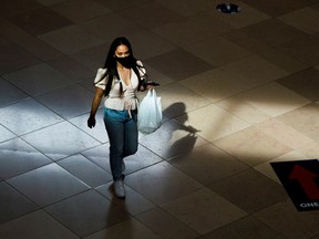 A shopper is illuminated by a beam of light as she walks down a hallway in Sherway Gardens Mall, in Toronto.