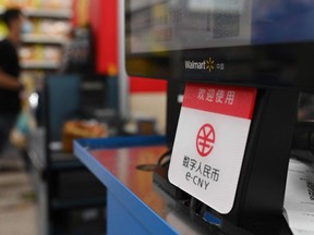 A sign indicating payment is accepted using China's new digital currency is seen at a checkout in a Walmart store in Beijing.