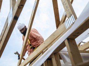 A worker climbs through the rafters of a home under construction by Akash Homes in Edmonton, Alberta.
