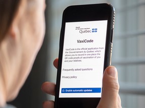 A woman looks at the Quebec government's new vaccine passport called VaxiCode on a phone in Montreal.