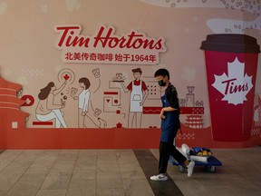 A man walks past a store front poster advertising the opening of a cafe of the Canadian coffee and fast food chain Tim Hortons in Beijing, China.