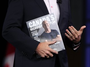 Erin O'Toole, leader of Canada's Conservative Party, holds a magazine featuring his recovery plan during a campaign event in Ottawa.