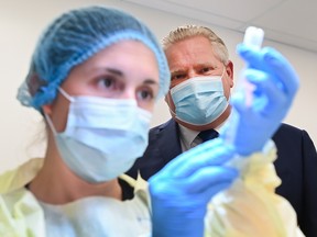 Ontario Premier Doug Ford watches a health-care worker prepare a dose of the Pfizer-BioNTech COVID-19 vaccine at a UHN vaccine clinic in Toronto.