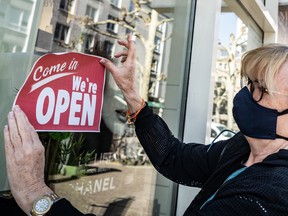 A shop owner places an open sign on her store window. Canadian businesses say they're expecting inflation to get worse.