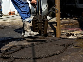 A member of a drilling crew prepares to place a collar around drill pipe on an oil rig in the Permian Basin near Wink, Texas.
