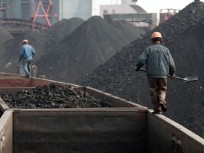Workers stand on a train to monitor the loading of coal at a coal depot in Shanghai, China .