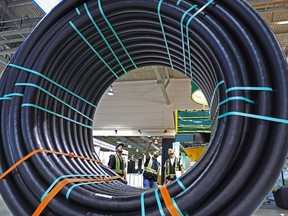 Workers check out a spool of pipe on display at the FlexSteel booth at the Global Petroleum Show in Calgary in 2018. The annual event — now called the Global Energy Show — has been postponed to 2022 due to rising COVID numbers.
