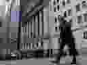 A man walks past the New York Stock Exchange on Wall Street in New York City. 