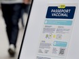 People walk by a sign at a restaurant advising customers of Quebec’s COVID-19 vaccine passport in Montreal, Sept. 6, 2021.