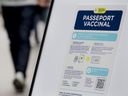 People walk by a sign at a restaurant advising customers of Quebec's COVID-19 vaccine passport in Montreal, Sept. 6, 2021.