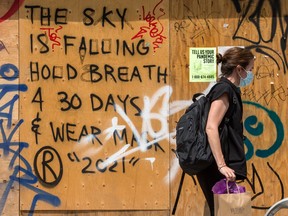 A pedestrian walks past graffiti in Toronto’s Kennsington Market during the COVID 19 pandemic.  Recent data showed the economy slumped in the second quarter.