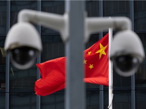 The flag of China is flown behind a pair of surveillance cameras outside the Central Government Offices in Hong Kong, China.