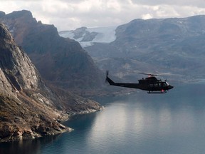 A Canadian military Griffon helicopter flies along the shoreline of Baffin Island as it moves personnel between Operation Nanook and Iqaluit, in 2014.