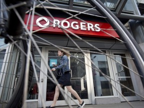A pedestrian passes in front of a Rogers Communications Inc. store in Toronto.