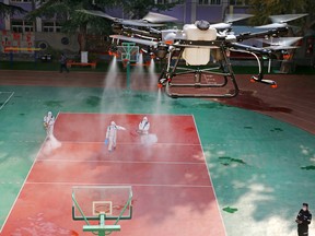 A drone sprays disinfectant over volunteers disinfecting a school following local cases of the coronavirus disease (COVID-19) in Lanzhou, Gansu province this week.