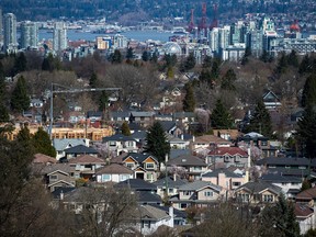 A condo building is seen under construction surrounded by detached houses as condo towers are seen in the distance in Vancouver, B.C.