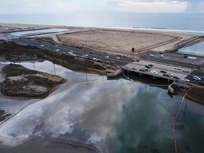 Environmental response crews cleaning up oil that flowed near the Talbert marsh and Santa Ana River mouth, creating a sheen on the water after an oil spill in the Pacific Ocean in Huntington Beach, California on Oct. 4, 2021.