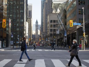 Morning commuters cross Yonge Street at Bay Street in the financial district of Toronto, on May 22, 2020.