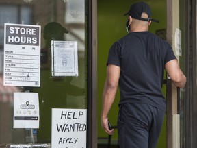 A person enters a roti restaurant on Toronto’s Bloor Street West with help wanted singage on June 9, 2021.