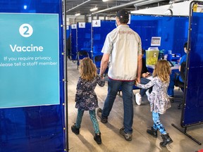 A man arrives with two young girls for his COVID-19 shot at the Ontario Food Terminal in Toronto on May 11, 2021.