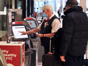 Travellers check in at the Air Canada desk at the Calgary International Airport on Nov. 26, 2020.