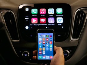 An iPhone is connected to a 2016 Chevrolet Malibu equipped with Apple CarPlay apps.